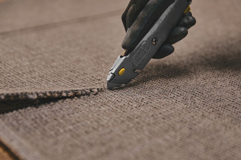 6 and 3 eighths inch Quick change retractable utility knife cutting woolen sheet.